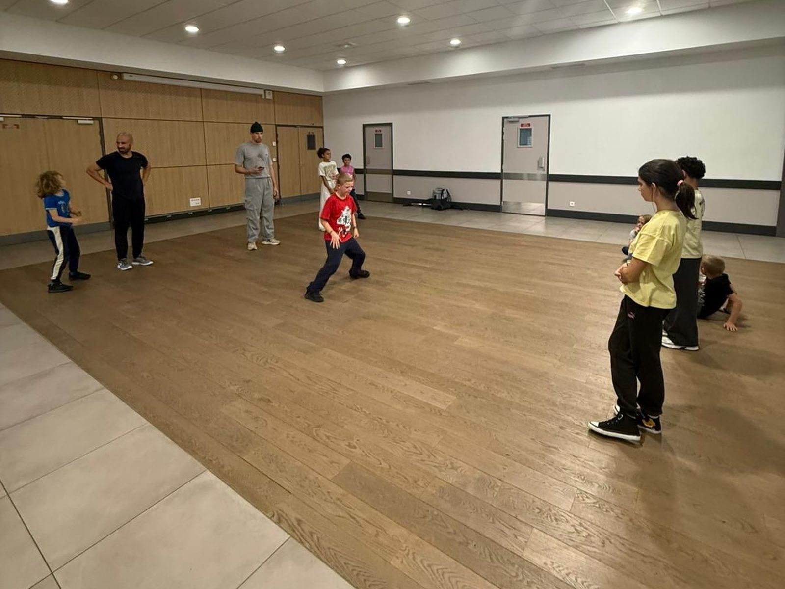 Un élève danse au centre de la salle pendant que le reste du groupe le regarde